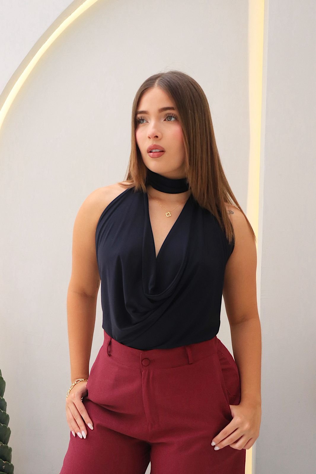 Blusa Aria en acetato doble tela, con diseño drapeado, tira al cuello y detalle de realce en el escote. Disponible en tallas S y M.