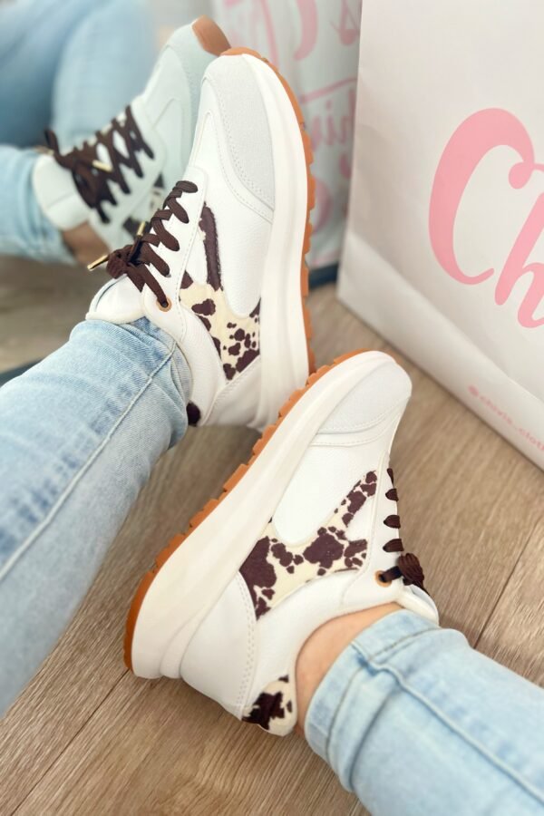 Tenis Amalia Cow en blanco con detalles en beige y gamuza estampada de vaca tono mocca, estilo sport elegante.