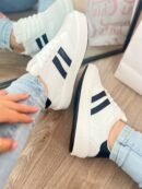 Tenis Santa blancos con líneas negro y punta en gamuza, estilo versátil y cómodo.