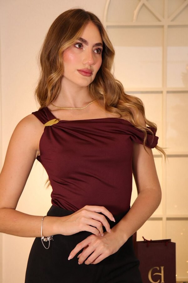 Blusa Tessa en acetato de doble tela con caída drapeada en los hombros, escote medio beso y detalle de hebilla lateral.