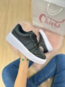 Tenis negros de suela baja con diseño cómodo y detalle dorado decorativo en la zona de los cordones.