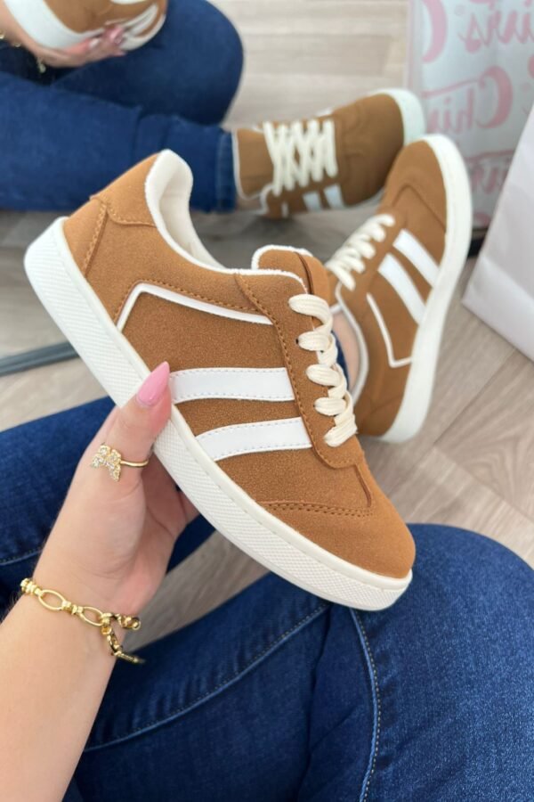 Tenis Addi miel con detalles verdes, suela color café y tres líneas laterales verdes. Diseño cómodo, versátil y moderno para uso diario.