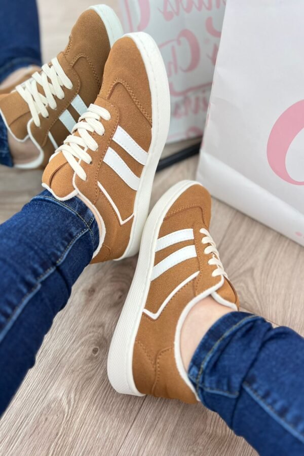 Tenis Addi miel con detalles verdes, suela color café y tres líneas laterales verdes. Diseño cómodo, versátil y moderno para uso diario.